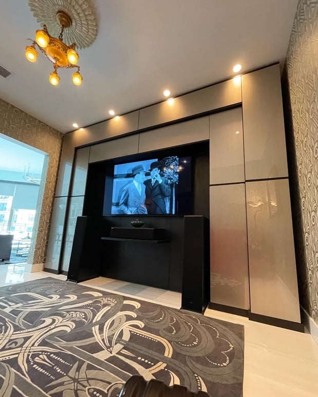 The theater room features a custom Proscenium design with Shadow Black and Metallic Champagne Northern Contour doors, including unique top-hinged, side-mounted doors, blending standard components with a stacked Virtuoso system.