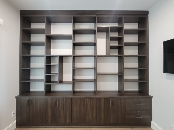 Custom office shelving designed in a dark wood grain finish. Use closed storage for items you want to keep hidden and open shelving for items you want to keep on display.