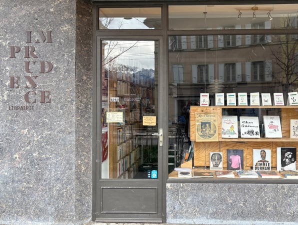 Façade de la librairie L'imprudence, Rue d'Italie 26 à Vevey, Nos voisins immédiats : Tami Hopf - graphiste7tatoueuse, Chez Gérard - coiffeur, Aujourd'hui - graphisme/impression taille douce, Le bout du Monde - bar associatif, Théâtre l'Oriental