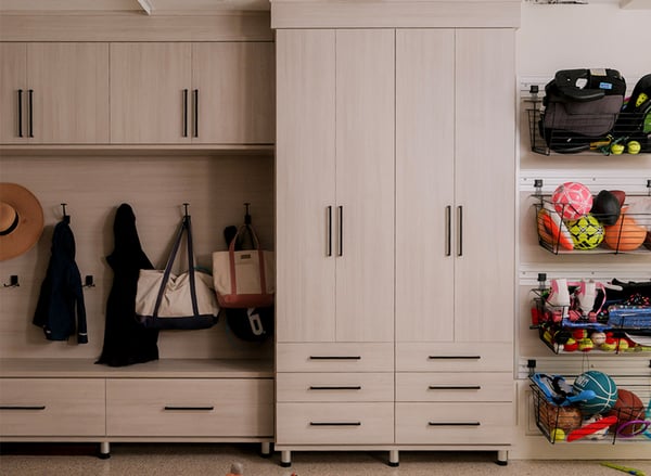 Custom garage storage with tall cabinets, drawers, hooks and wall-mounted sports equipment organization by California Closets Nashville.