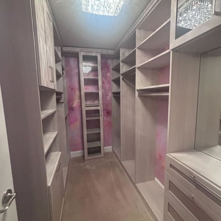 Richmond - Custom closets - walk-in closet with light wood shelving, drawers, glass-front cabinets, and a crystal chandelier overhead
