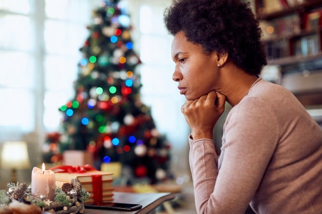 Woman Stressed Out Next to Fully Decorated Christmas Tree