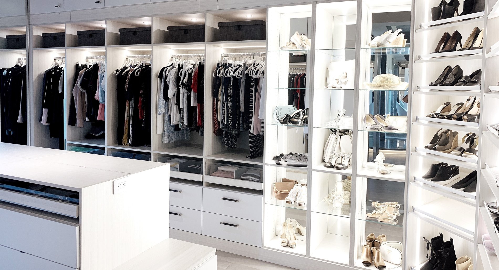 luxury walk-in closet with lighting,display shelving, and an island