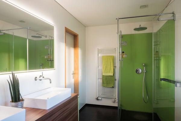 Mit den grünen Glasrückwänden und den holzfarbigen Waschtischunterbauten ist ein perfektes Frühlingsbad entstanden.