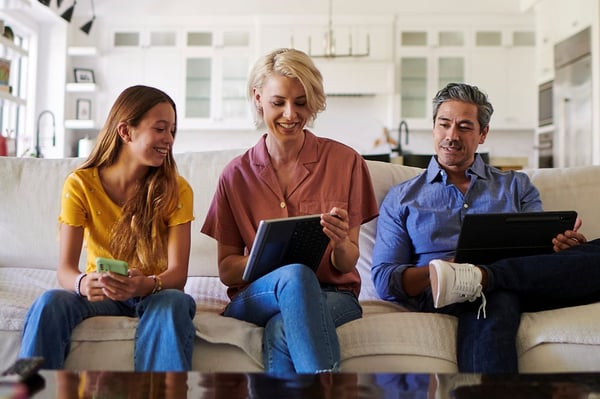 Familia en un sillón usando dispositivos para conectarse a Wi-Fi