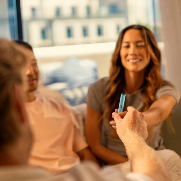 2 barbati și o femeie care ține un IQOS în mână.