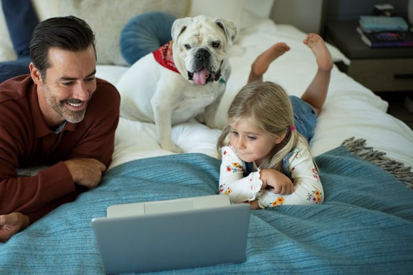 Daddy daughter streaming on bed with their pet dog