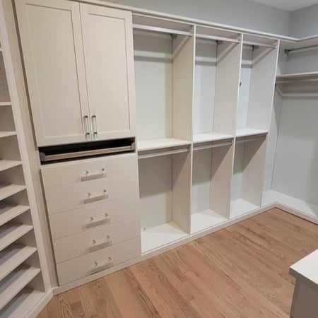 A white walk-in closet with dividers and shelves for organized storage.