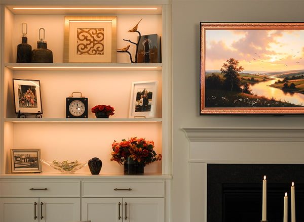 Custom living room built-in shelving and entertainment center surrounding a TV by California Closets Nashville. Designed in Classic White with gold hardware.