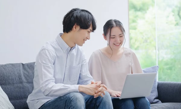 パソコンを見ながら微笑むカップル