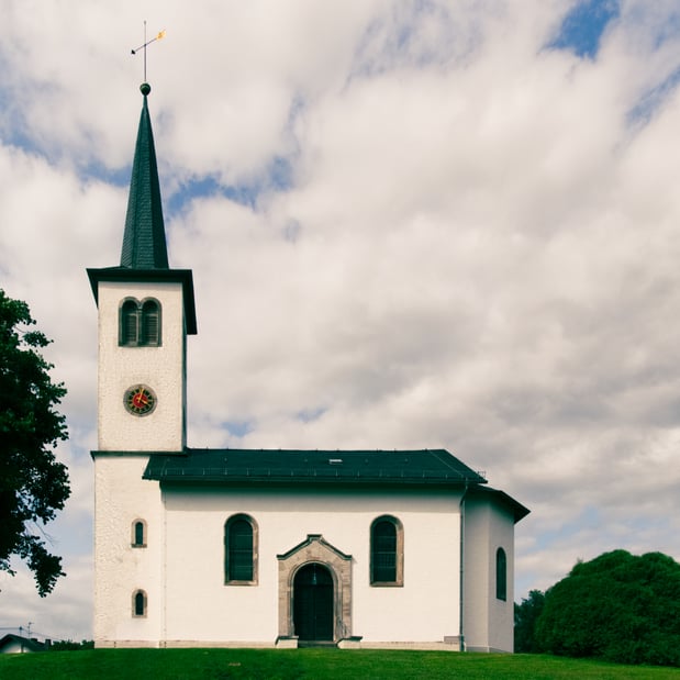 Die heutige Kirche wurde am 10. August 1852 eingeweiht. Sie steht auf dem Hügel, auf dem die erste Kapelle in Freirachdorf im 15. Jahrhundert gebaut wurde und wegen Baufälligkeit abgerissen werden musste. Besondere Schmückstücke sind die Sakramentsfenster im Chorraum, auf denen Christus in der Mitte, Mose und Paulus zu je einer Seite abgebildet sind. Der große Kronleuchter im Kirchenschiff ist aus 400 Jahre altem Eichenholz geschnitzt.