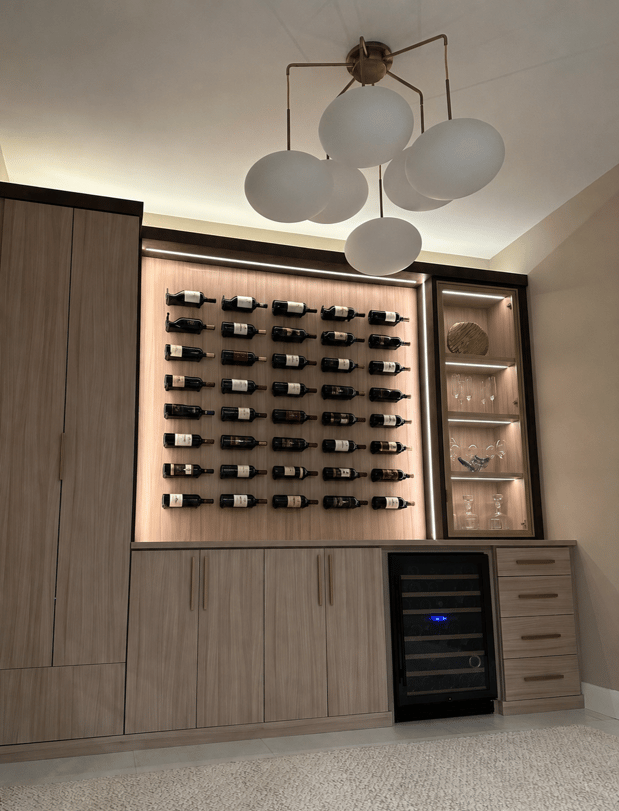 Custom wine storage with wall-mounted bottle display, wood cabinetry, glass shelving, and wine refrigerator.
