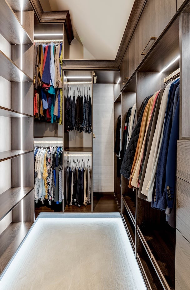 custom walk-in for him with dark wood, hanging rods, integrated lightings