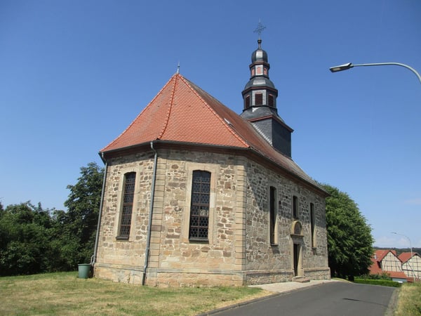 Das Bild zeigt die Evangelische Kirche Wahlen von außen. Die Kirche hat ein rotes Ziegeldach und eine spitzen Kirchturm.