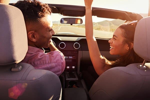 smiling couple in a convertible car with auto insurance from a AAA Agent
