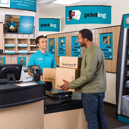 Smiling associate reaching out their hands to receive packages from smiling customer