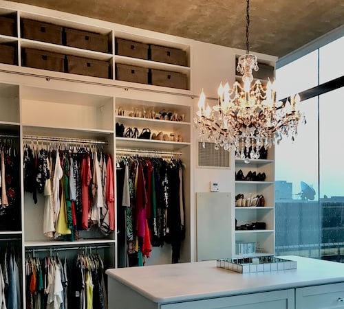 Walk-in closet with high storage, shelving, cabinets, island in white wood by California Closets Chicago.