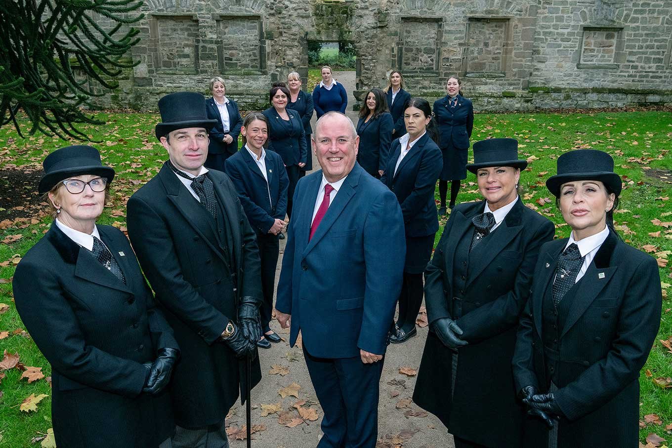 Funeral directors and arrangers wearing traditional outfits stand together