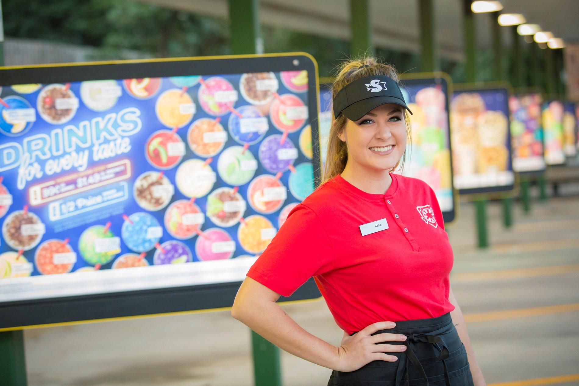 sonic employee smiling in front of menu board