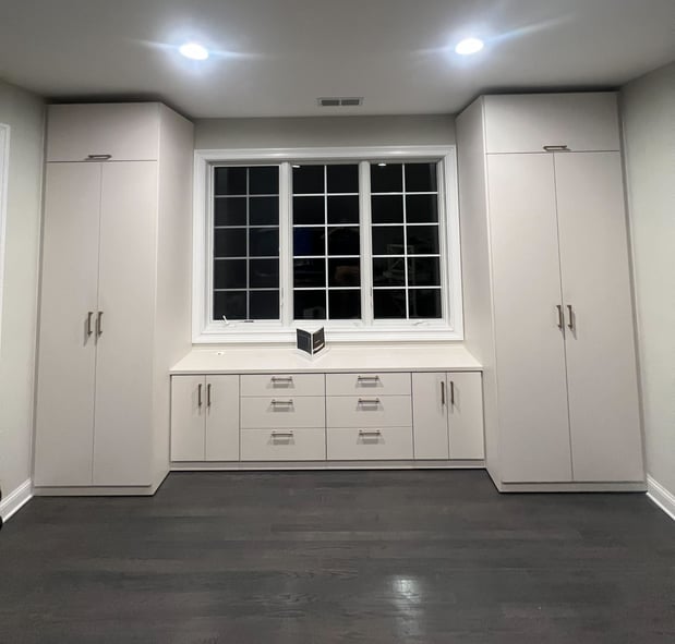 Light office wall unit with floor-to-ceiling closed storage, drawers, and countertop