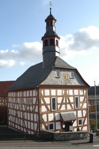 Das Bild zeigt die Außenansicht der Evangelischen Kirche  Feldatal-Ermenrod. Die Kirche wurde im Fachwerkstil gebaut und ein Kirchturm markiert die Spitze.