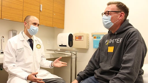 Photo of UC San Diego Health orthopedic surgeon Dr. James Flint, left, and his patient Colin Jackson during a patient visit.
