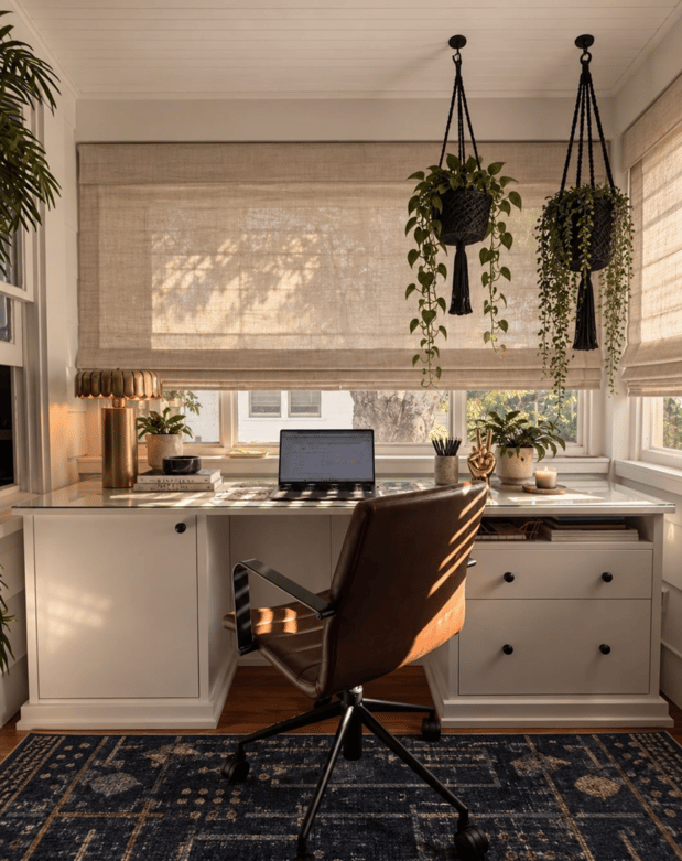 Custom home office with white built-in desk, cabinetry, drawers, and storage beneath large windows.