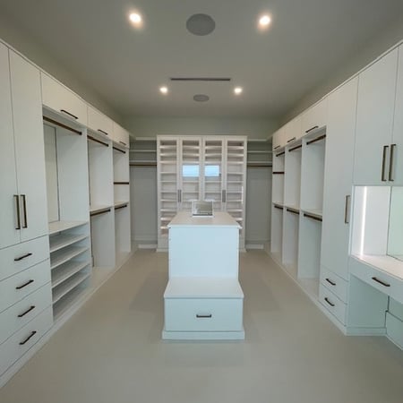 Master closet with Dove finish, Modern Elite gold hardware, and clear glass inserts.