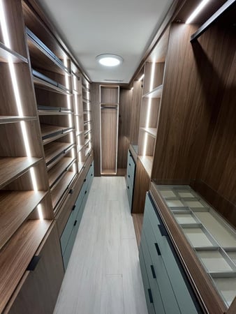 custom walk in closet features lighting, jewelry trays, backing and mixed finishes