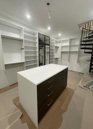custom walk in closet with shelving, hanging rods, and an island