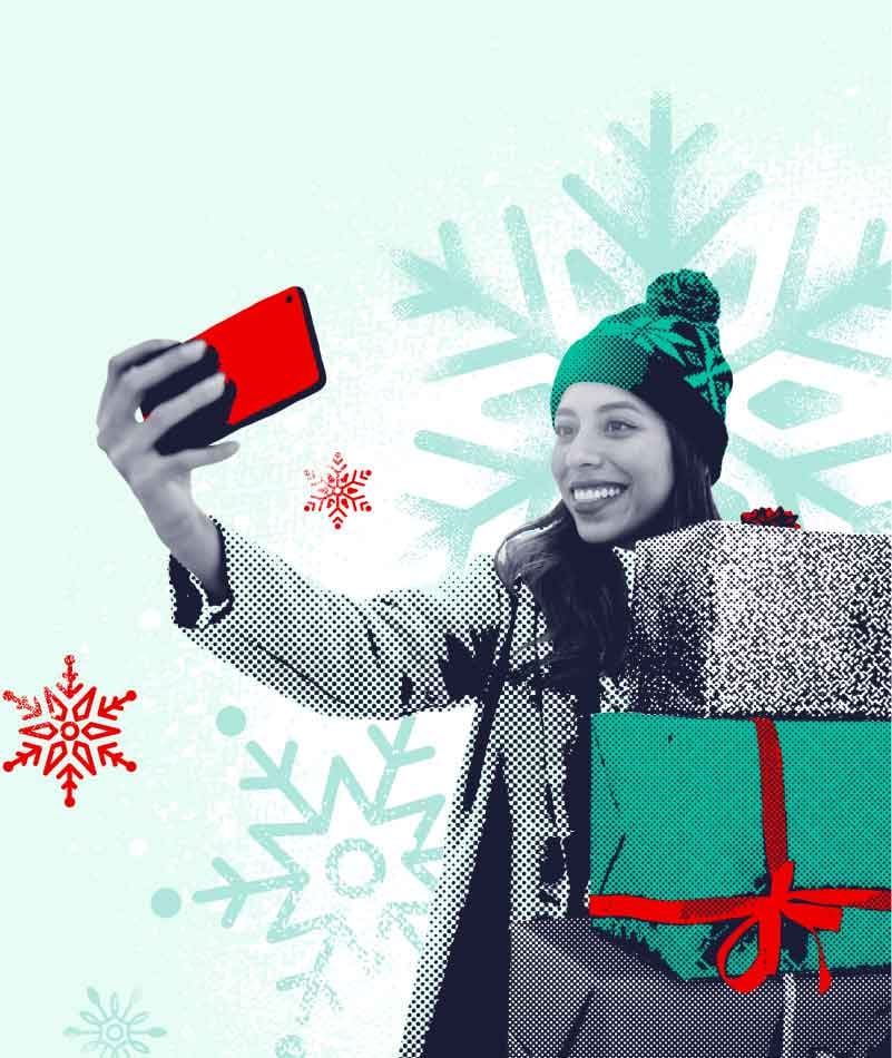 Mujer sonriente con gorro de invierno tomándose una selfie mientras sostiene un regalo envuelto, con un fondo de copos de nieve.