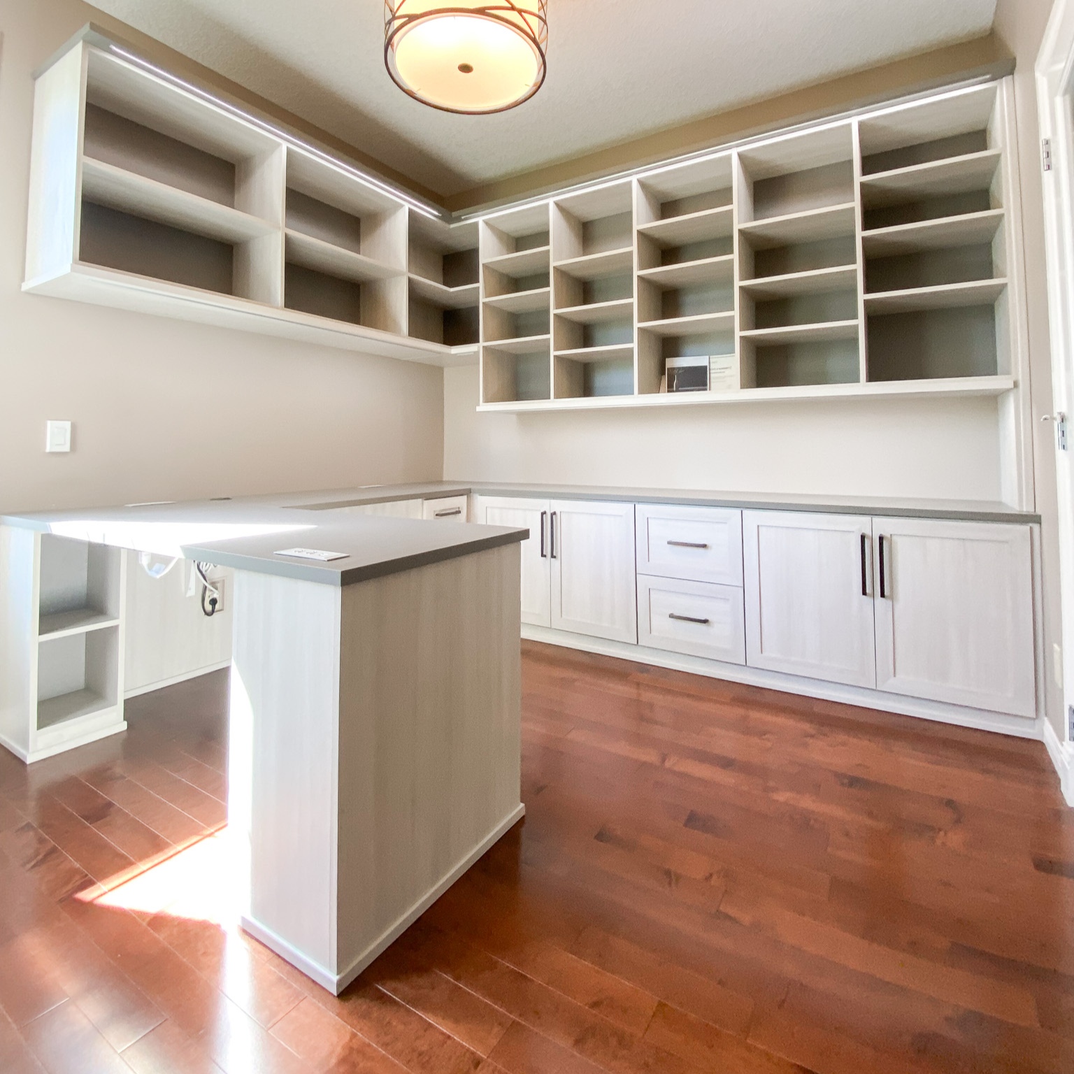Home office with work station, lower cabinets and open upper shelves.