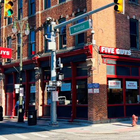 Exterior photograph of the entrance to the Five Guys restaurant at 508 Monroe Street in Detroit, Michigan.