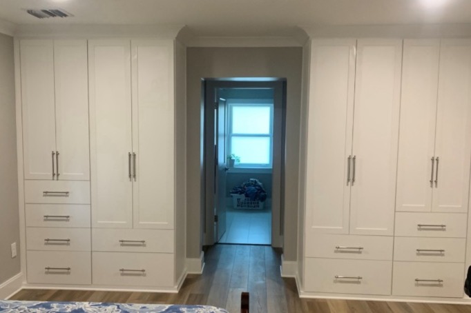 Custom master bedroom wardrobe in dove white with square mitered doors, matte nickel hardware, and classic crown molding—designed to expand storage in a room with limited closet space.