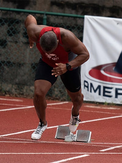 Man in athletic gear about to run on a running track