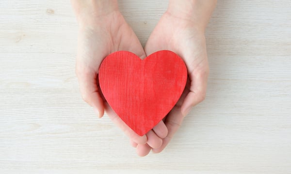 ハート型の木のおもちゃをもって見せている両手のアップ