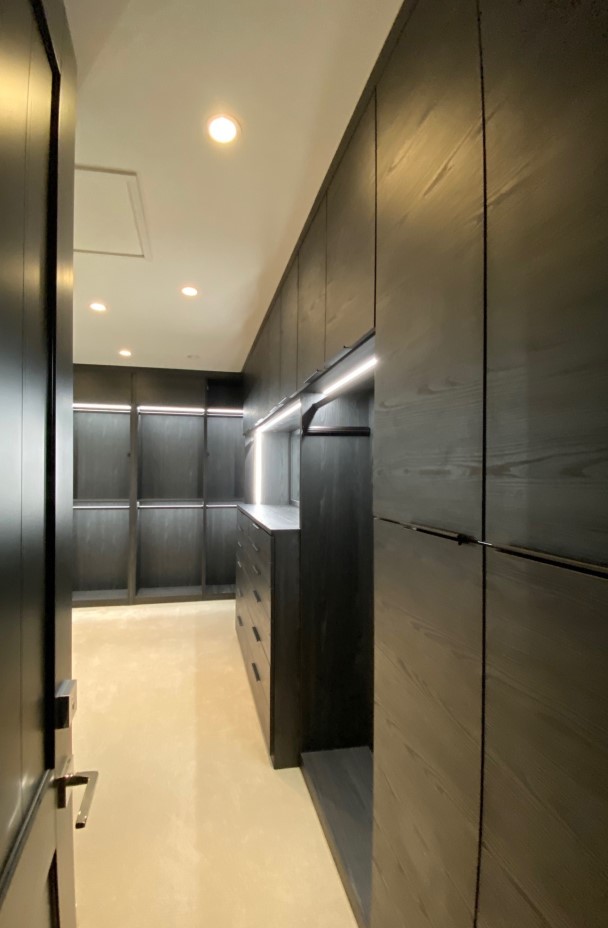 Large walk-in closet in dark finish with recessed lights and mirror.