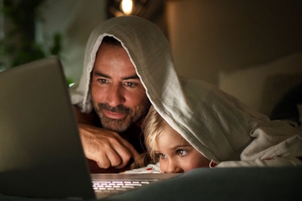 Dad and daughter streaming a movie on a laptop