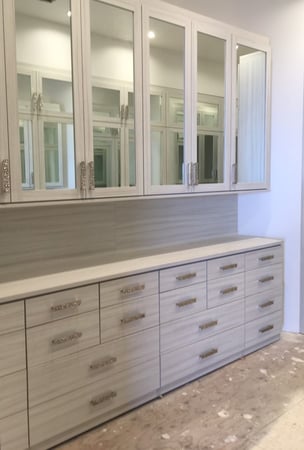 Floor to ceiling wardrobe system in a light finish with drawer stacks and mirror glass doors on upper cabinets.