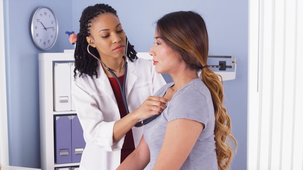 A primary care physician listens to a patient's heartbeat using a stethoscope.