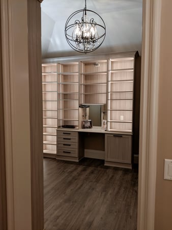 Luxurious walk-in closet with a chandelier and built-in vanity.