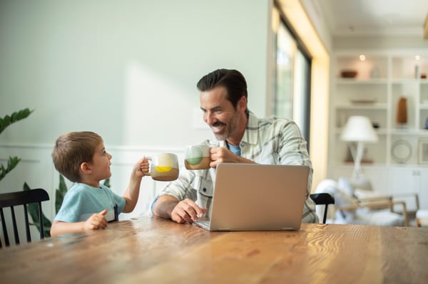 Father on laptop with son at kitchen table