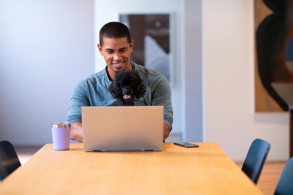 Man working remotely on laptop with a dog