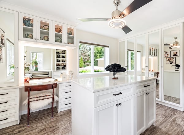 Bright walk-in closet with custom closet organization, built-in cabinets, drawers, shelving, island, and vanity for elevated storage, California Closets Northern Michigan