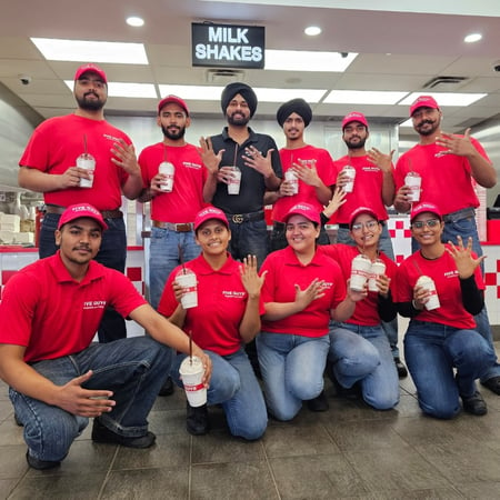 Employees pose for a photograph holding milkshakes outside the kitchen ahead of the reopening of the Five Guys restaurant in East Gwillimbury, Ontario, Canada.