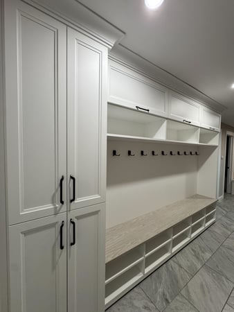 White mudroom with bench, shoe cubbies beneath and flip-up cabinets above