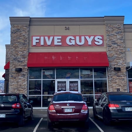 Exterior photograph of the entrance to the Five Guys restaurants at 34 East Allen Street in Castle Rock, Colorado.