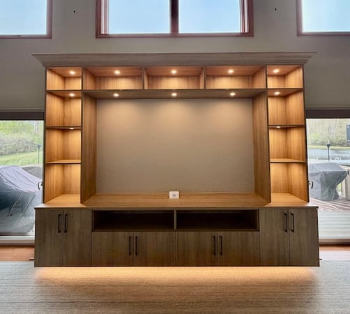 Custom built-in entertainment center featuring open shelving, media storage cabinets, integrated lighting, and custom cabinetry for organized living room storage. This modern media center by California Closets includes floating shelves, built-in cabinets, and functional home organization designed for electronics, décor, and entertainment storage.