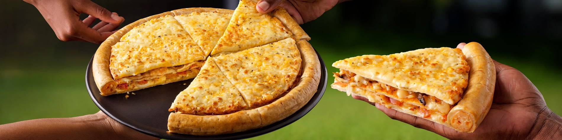 A large Cram-Decker® pizza on a plate with hands grabbing a slice.