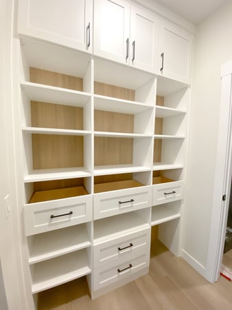 White organized pantry with contrasting backing, open shelving, and drawers.